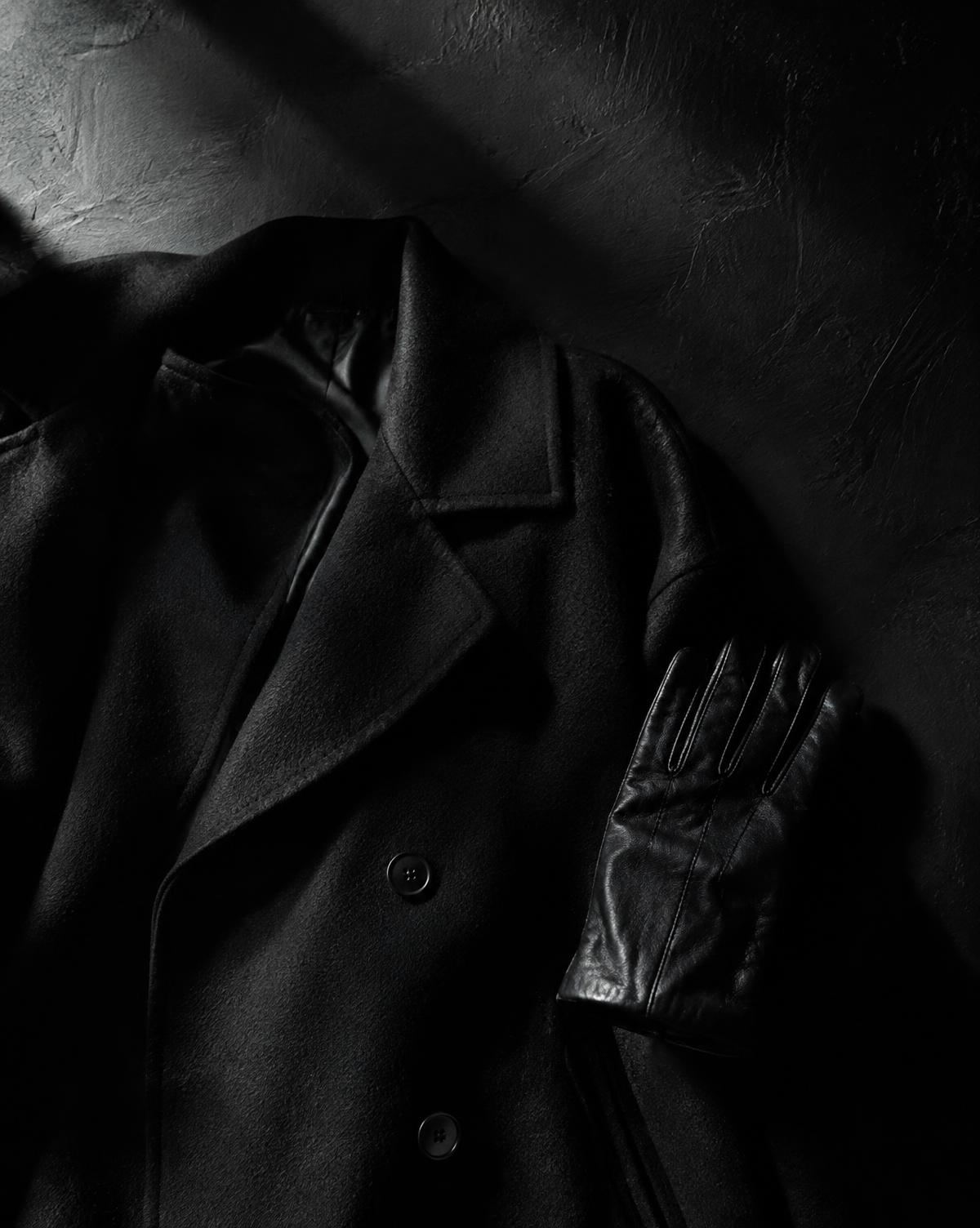Black wool coat and leather glove under raking light