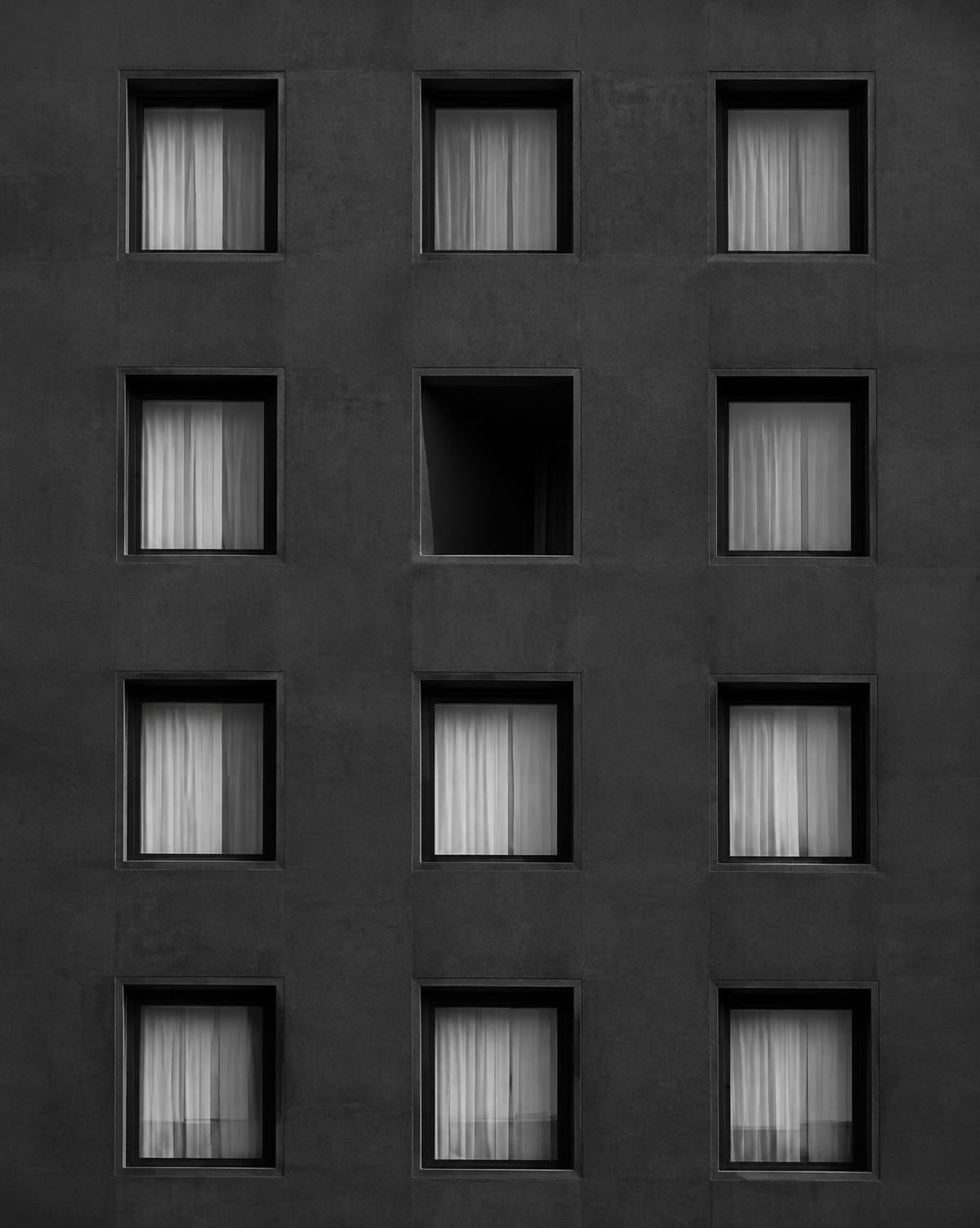 Concrete façade of repeated windows with one open