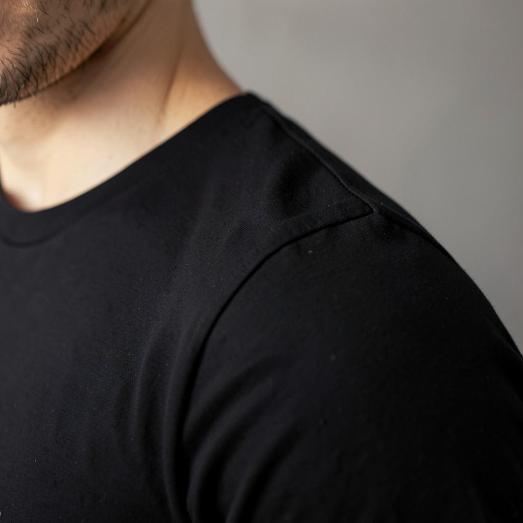 Shoulder seam sitting cleanly at the edge of the shoulder on a plain black T-shirt