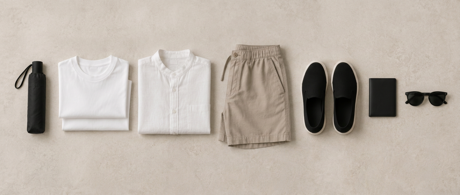 A flat lay of lightweight T-shirts, a linen shirt, neutral shorts, black slip-on sneakers, sunglasses and a compact umbrella for a Hong Kong summer trip