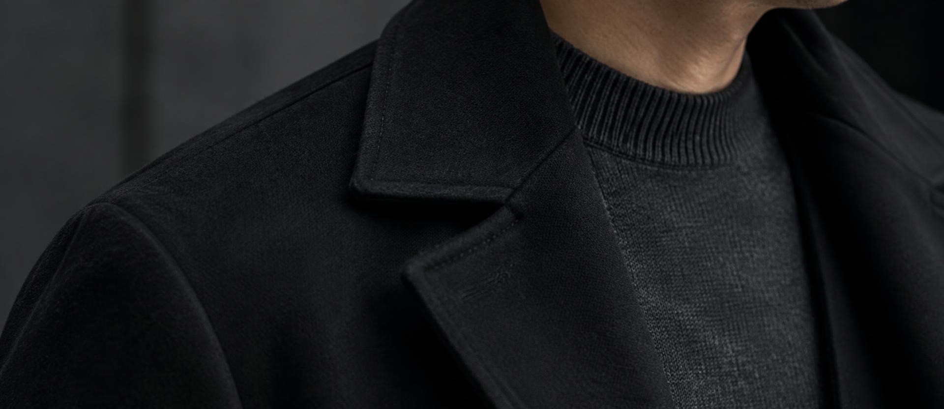 Détail d'un pull fin anthracite sous le col d'un manteau noir ouvert