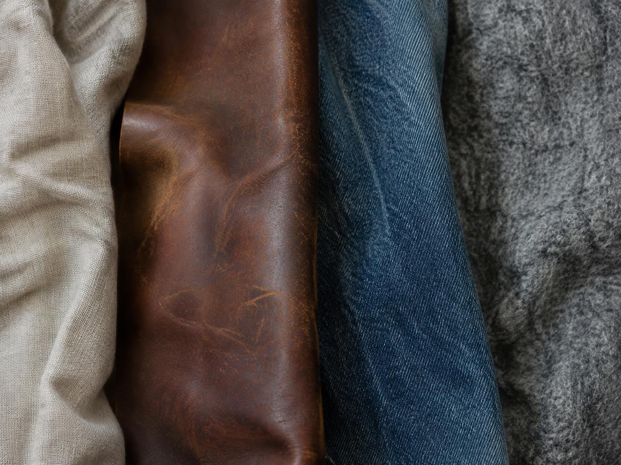 Softened linen, marked leather, faded denim and settled wool side by side