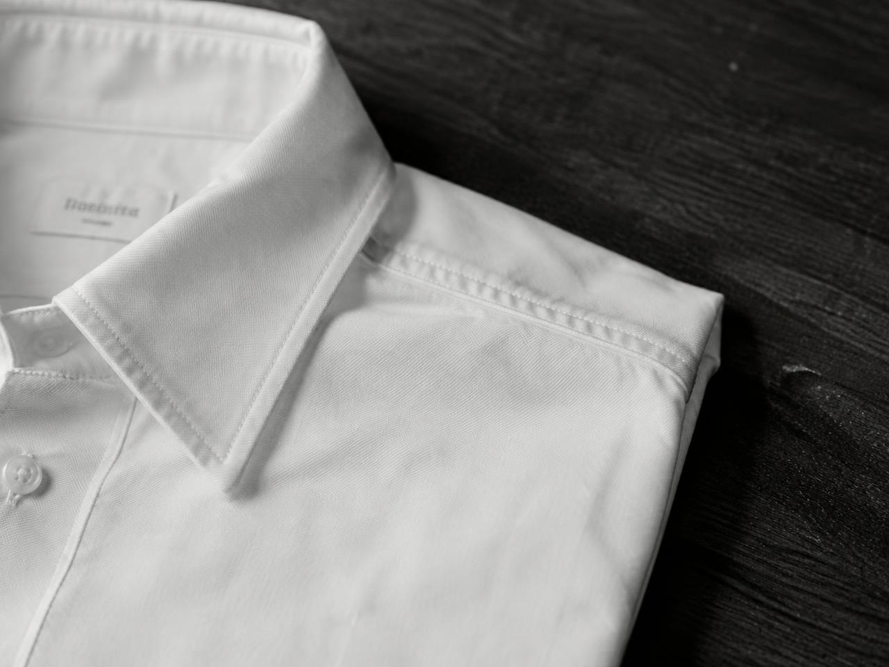 A folded white cotton shirt showing its collar and shoulder seam