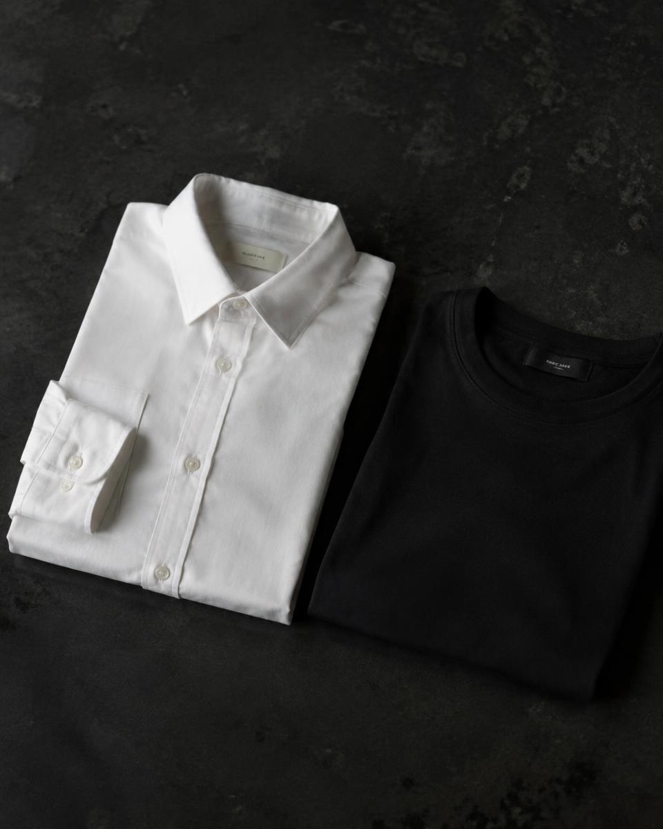 Folded crisp white cotton shirt beside a soft black jersey T-shirt